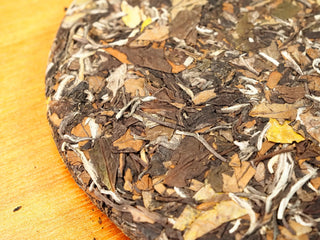 Close-up detail of the 2020 Fuding White Peony cake surface, revealing silvery buds and aged brown leaves bound together.