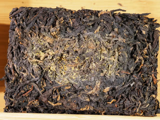 Texture of aged dark tea leaves in a Chang'an Qianqiu Golden Flower Fu Brick.