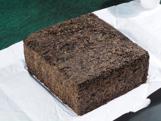 Side view of the 2013 Fu Brick dark tea, highlighting the dense and naturally aged compressed leaf texture.
