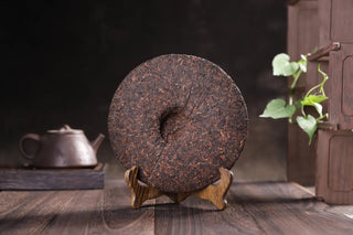 8-year aged Ripe Pu-erh tea cake on display stand with traditional tea set