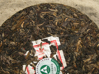 Close-up of 2006 Mangbo raw Pu-erh tea leaves with embedded authenticity label (Neifei).