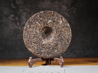 Unwrapped back side of Ancient Arbor Harmony Raw Pu-erh Tea cake revealing natural leaf pattern of ancient tree leaves.