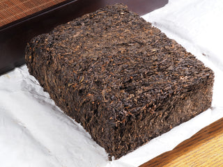 Close-up of the artisanal hand-hammered Fu Brick surface, showing the tightly pressed dark tea leaves.
