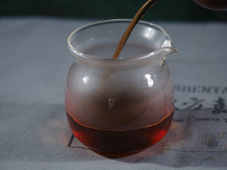 Rich, dark, and clear tea liquor of dry-aged Imperial Puerh served in a glass pitcher, reflecting a smooth and mellow body.
