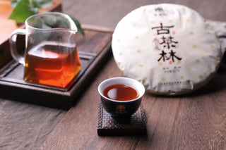 Deep reddish-brown tea liquor of 2019 Chunming ripe Pu-erh served in a traditional Gongfu tea set.