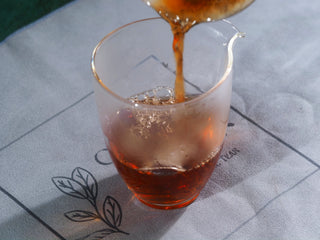 Deep amber and clear ripe Puerh tea liquor brewed from Lao Cha Tou nuggets, served in a glass pitcher.
