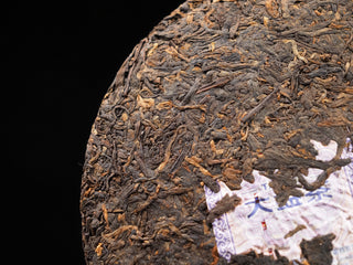 Close-up of the compressed dry tea leaves of 2017 Dayi 7452 ripe puerh cake with the embedded inner trademark label (Neifei).