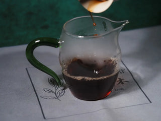 Decanting the clear ruby red liquor of 2013 Aged Liubao Dark Tea from a Gaiwan into a glass Fairness Pitcher to ensure an even taste.