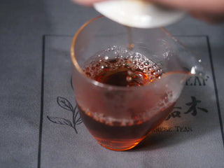Clear amber tea liquor of Huang Guan Yin Oolong being poured into a glass pitcher (Gongdao Bei).