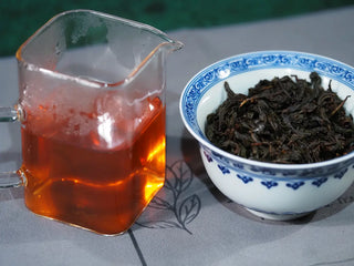 Jin Guanyin (204) Floral Wuyi Rock Oolong tea liquor in a fairness pitcher displayed beside the opened wet leaves, showing clarity and bright floral aroma.