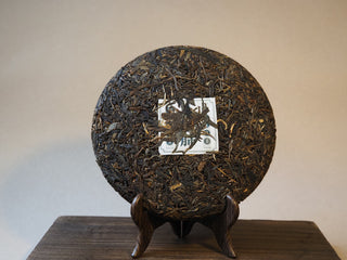 Unwrapped 357g Mangfei Mountain ancient tree raw Pu-erh tea cake front view
