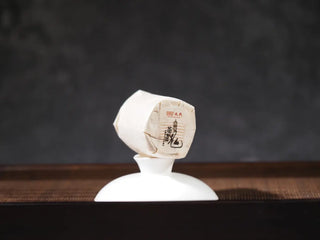 Paper-wrapped Mengku TeaSoul Sheng Pu-erh Coin Tea inside mini box, ready for single serving brewing