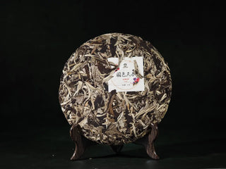 Front view of unwrapped Yunnan Jinggu White Peony Tea Cake 357g, displaying silver-green leaves and round pressed cake form