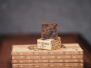 Close-up of the 4g single-serving Yunnan Mini Ripe Pu-erh Tea Brick and its individual wrapper, highlighting its compact travel-friendly design.