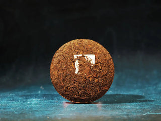 Unwrapped front view of the Yunnan Red Glow Ripe Pu-erh Tea Mini Cake – 100g, showing its tightly compressed high-mountain tea leaves.