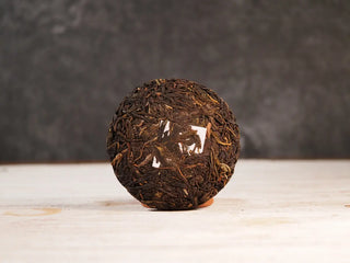 Snow Mountain Rare Wild Ancient Tree Sheng Pu-erh (2016–2023) – 100g Mini Cake, front view unwrapped, displaying the compact and smooth tea cake