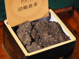Opened box revealing the dense, dark compressed tea brick of YXT Jingyang Golden Flower Fu Tea First Grade 300g.