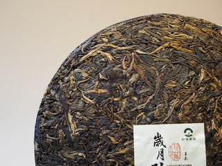 Close-up of the outer edge and compressed leaf texture of the 2005 Lincang vintage raw Pu-erh tea cake.