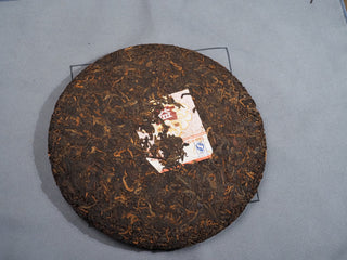 Unwrapped 2006 Dayi 7572 ripe Puerh tea cake showing compressed dark brown tea leaves