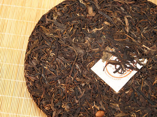 Close-up of Jing Chang Hao Mengsong Autumn Harvest 2013 raw Pu-erh cake surface, dark arbor leaves with golden buds