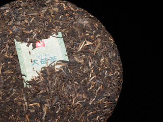 Macro shot of the trademark Neifei label embedded in the 2016 Dayi 7532 Sheng Puerh tea cake, showcasing dried leaves texture.