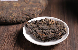 Close-up of 2019 Chunming ancient tree ripe Pu-erh tea leaves and a broken piece from the cake.