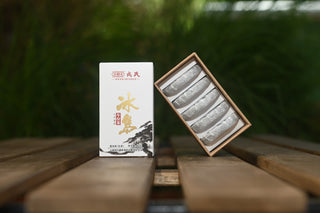 Small gift box of Mengku Rongshi Bingdao Aged Raw Pu-erh coin cakes: one closed, one opened showing 5 silver-wrapped coins.