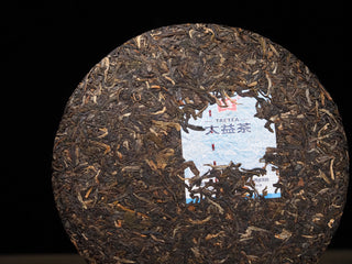 Close-up of the compressed dry leaves and embedded trademark ticket (neifei) on a 2021 Dayi Mi Xiang Raw Puerh cake.

