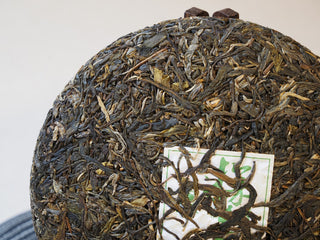 Close-up surface detail of the compressed 2025 Tan Chun raw Puerh tea cake showing robust leaf structure.