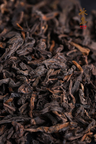 Close-up of Mengku Rongshi Bingdao Aged Ripe Pu-erh dry leaves, dark fermented leaves with golden buds piled in a heap.