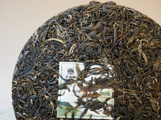 Close-up surface detail of the compressed 2026 Tan Chun raw Puerh tea cake showing robust leaf structure.