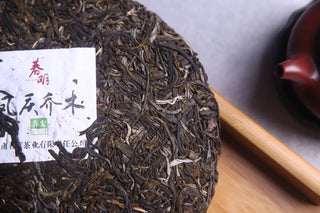 Close-up of the 2016 raw puerh tea leaves texture, highlighting the aged dark green and golden tones.