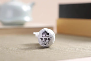 Close-up view of a hand-rolled Ancient Tree Raw Pu-erh Tea Dragon Pearl, showing the tight, pure leaf compression.