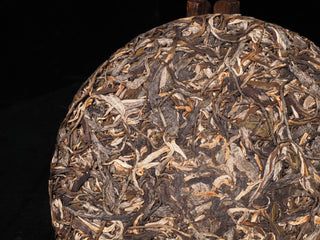 Close-up texture of Sheng Bulang Buds sheng Puerh cake surface showing premium spring harvest silver tips.