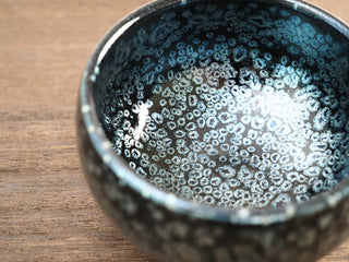 Close-up interior view of a Da Chan Ding Jianzhan tea bowl showing the densely packed silver oil-spot crystals with blue-green iridescence.