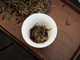 Broken pieces of dry loose Bai Mu Dan white tea leaves placed inside a traditional white porcelain gaiwan for an evaluation session.