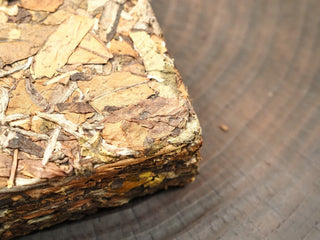 Close-up of Gold Brick 2012 White Peony brick corner revealing brown and green leaves with natural tea stems pressed firmly together.