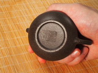 Underside of the Guyun Shipiao Yixing teapot showing the recessed foot, square maker seal and coarse sandy clay