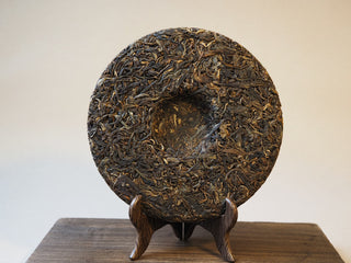 Back view of compressed Mangfei Mountain raw Pu-erh tea cake showing inner mold