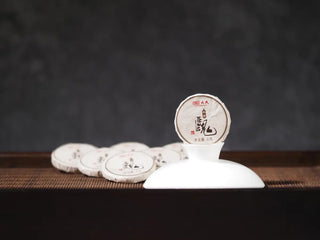 Close-up of Mengku TeaSoul Sheng Pu-erh Coin Tea in paper wrapping, showing premium craftsmanship