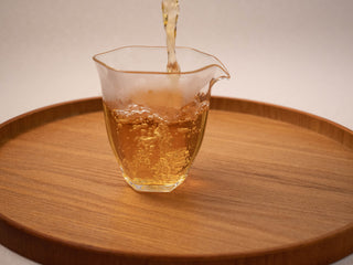 Pouring brewed Yunnan Golden Empress Oolong tea into a tasting cup
