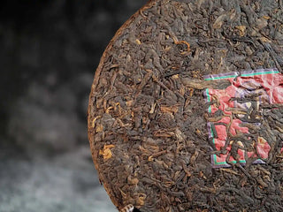 Close-up of the front of Qilin Hao Fengshan Gushu Ripe Pu-erh Tea Cake 2021 highlighting dark glossy leaves