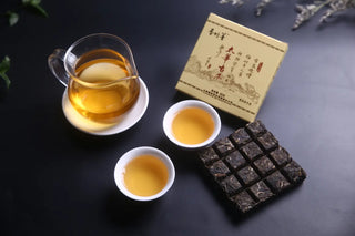 Two Cups of Clear Golden Taihua Ancient Tree Raw Pu-erh 2016 Tea Liquor Next to Waffle Tea Cakes, Perfect for Sharing.