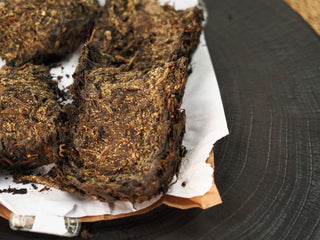 Broken pieces of The Little Brick fu brick tea revealing dense golden flower colonies distributed inside the compressed brick