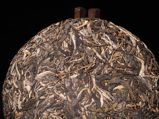 Close-up of unblended single-origin Lao Man'e ancient tree Puerh leaves on the cake surface, proving true material consistency.