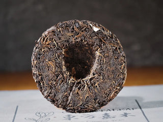 Back view of unwrapped Yiwu Raw Pu-erh Cake – 2013 Spring Tea, Hand-Pressed 2023, Sweet & Layered (100g), showing the compressed tea texture and craftsmanship