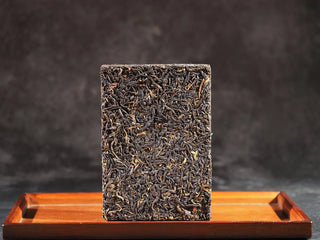 Full view of the compressed 1958 aged dark tea brick on a wooden display tray.