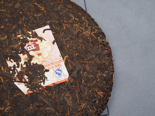 Close-up of 2006 Dayi 7572 shou Puerh cake with embedded original inner trademark paper