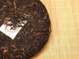 Side view of Jing Chang Hao Mengsong Autumn Harvest 2013 raw Pu-erh cake edge showing loosely compressed arbor leaves and nei fei corner
