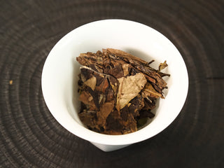 Dry 2013 Fuding Shou Mei leaves in a white porcelain gaiwan, displaying the coarse leaf and stem structure before brewing.
